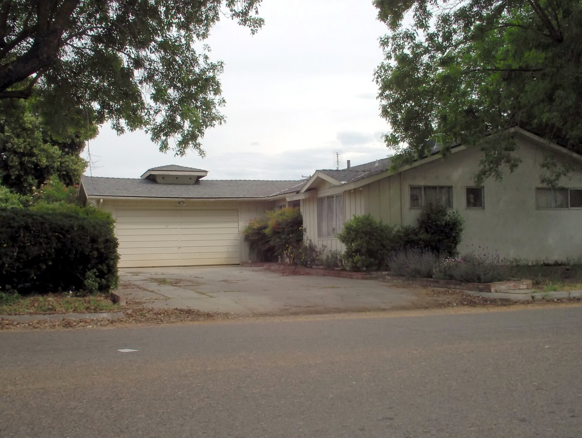 Long, low single-storey 1950s ranch-style house with board and batten siding and an attached garage