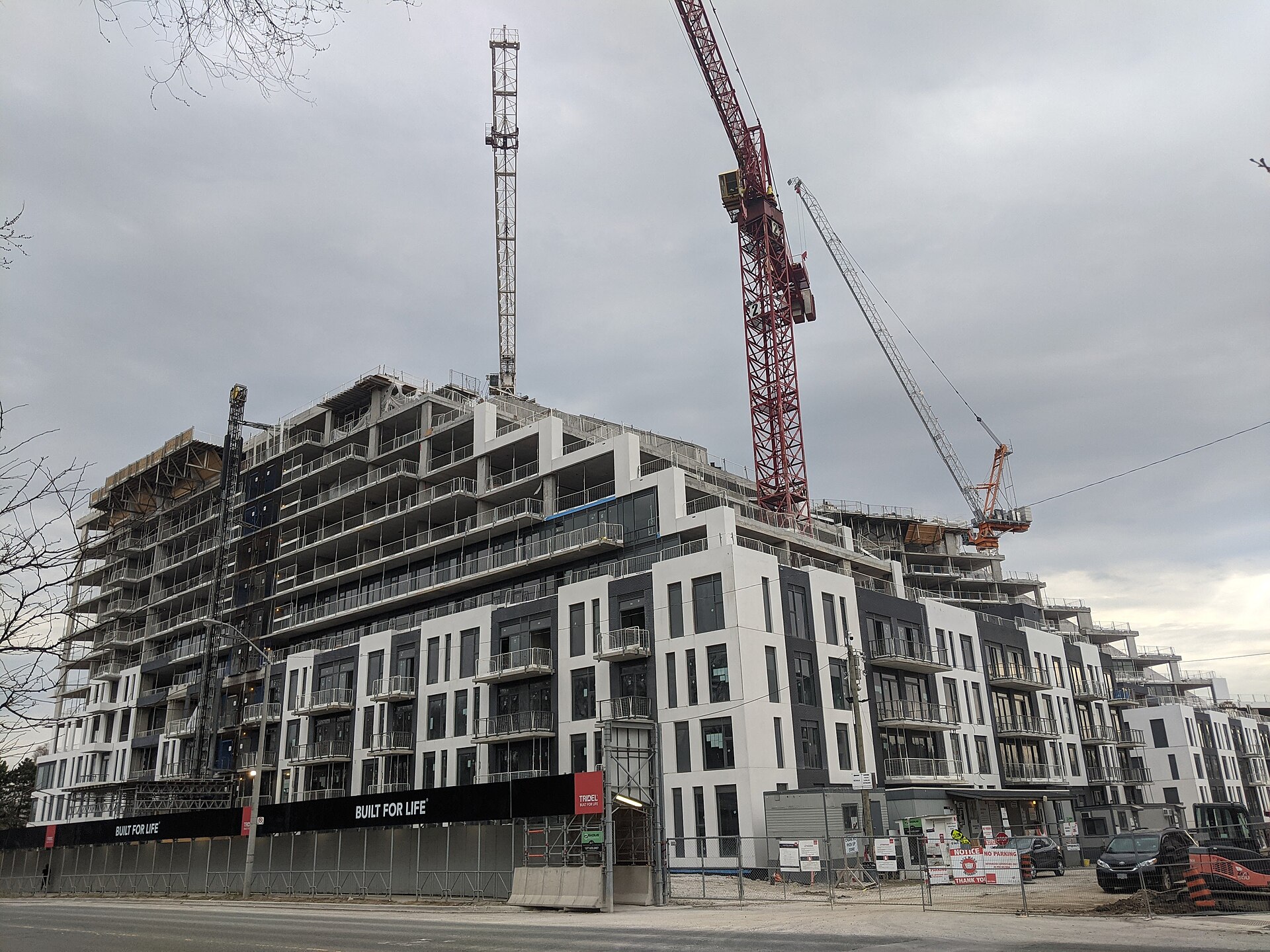 Mid-rise condominium building under construction with tower cranes overhead in Toronto