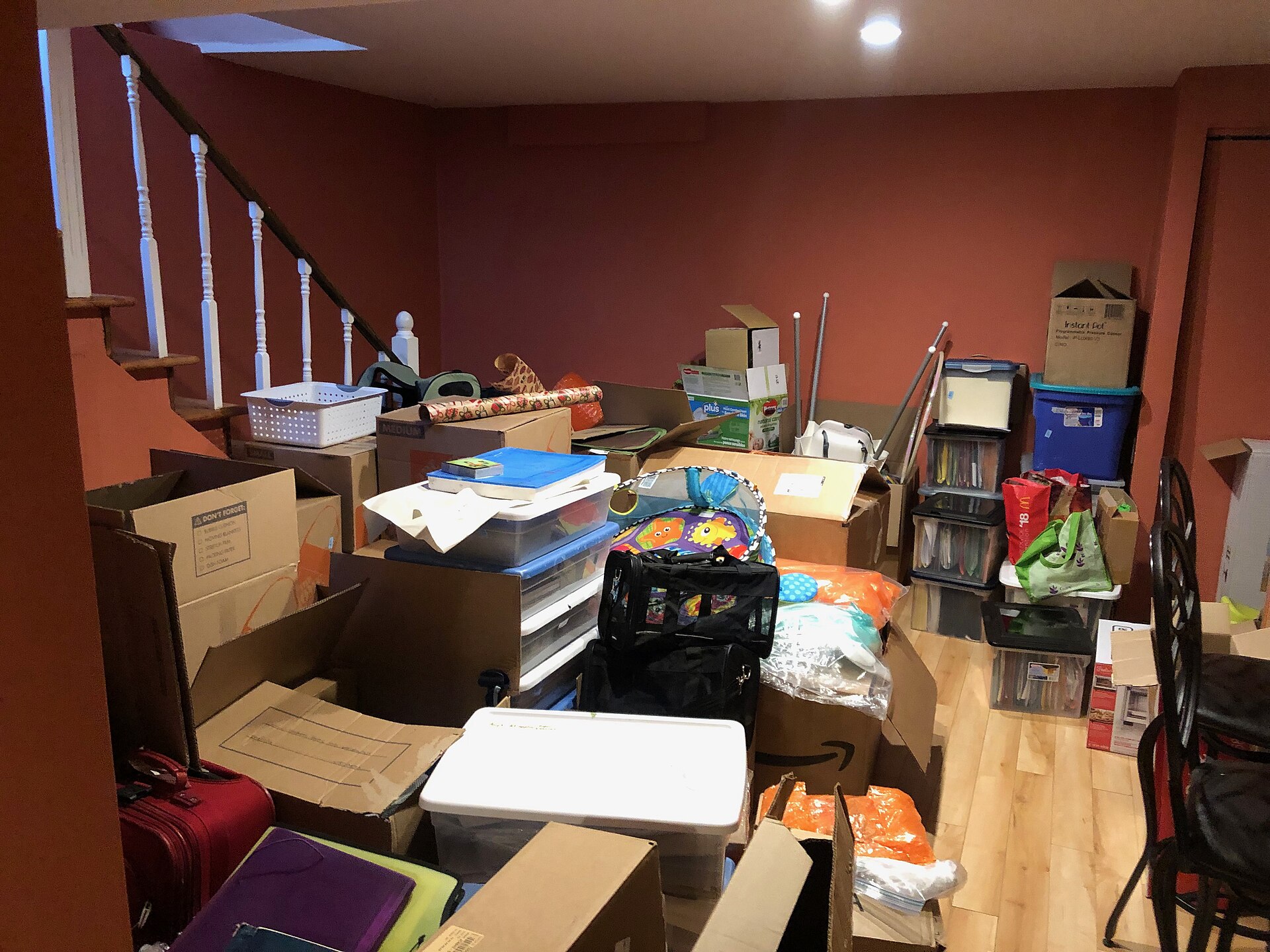 Basement crowded with stacked boxes, bins and household belongings waiting to be sorted