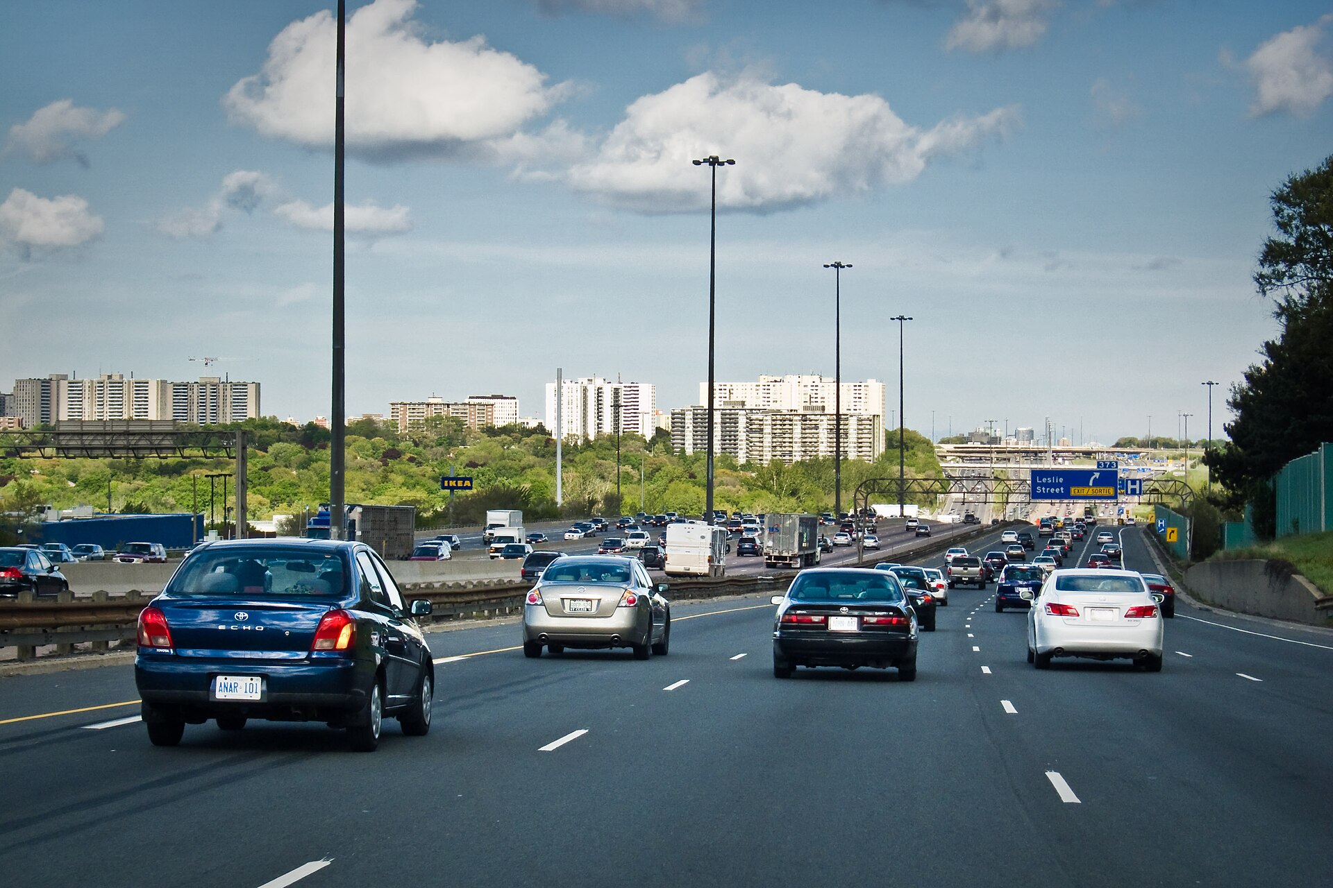 Heavy traffic on a wide stretch of Highway 401 near Leslie Street in Toronto under a cloudy sky