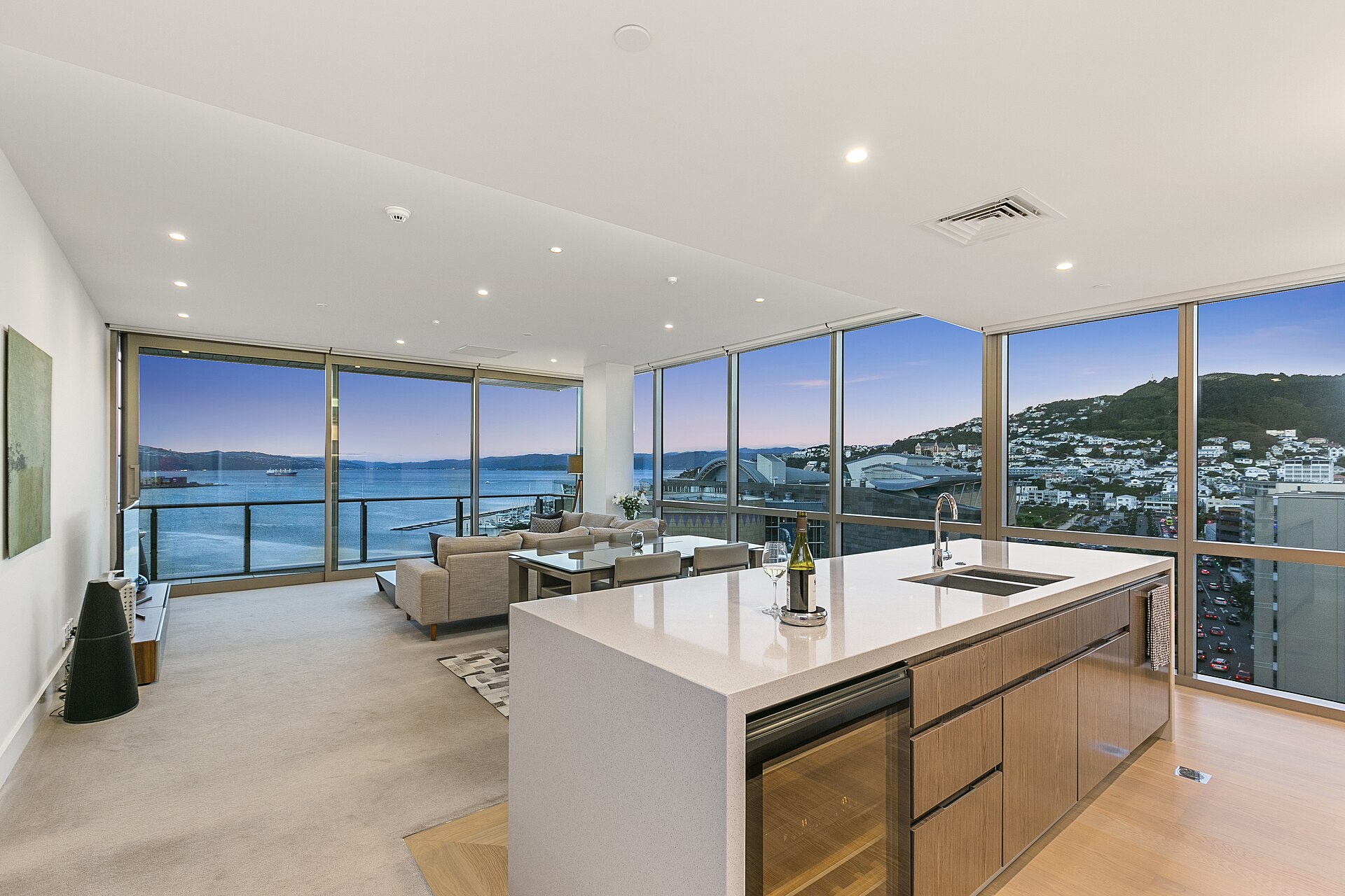 Bright open-concept kitchen and living room with large windows, photographed at dusk for a property listing