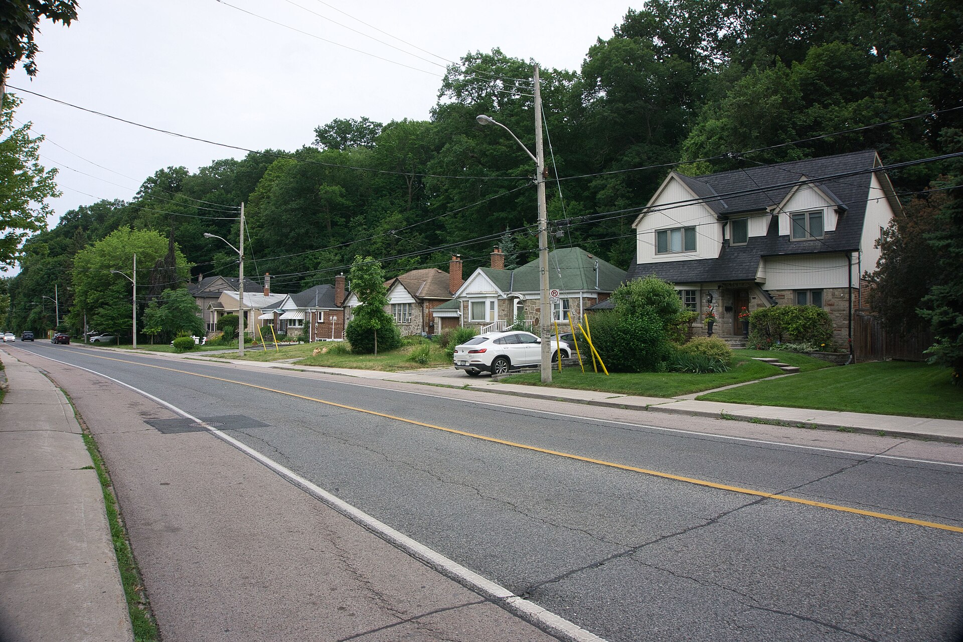 Detached houses set back on lawns along a tree-lined stretch of South Kingsway in west Toronto