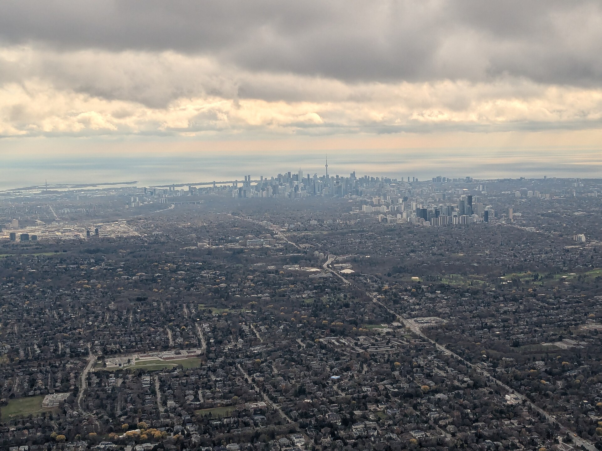 Aerial view from a plane window of Toronto’s downtown towers and low-rise neighbourhoods stretching to the horizon
