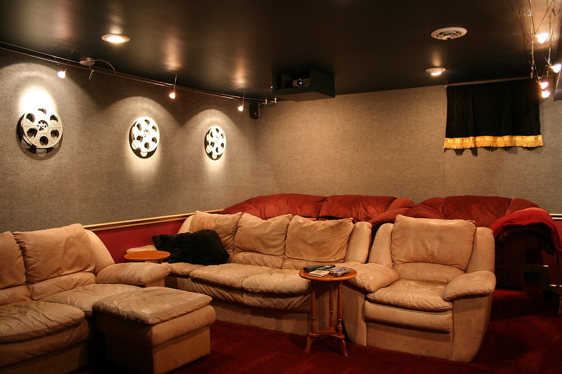 Basement home theatre with a large curved sectional sofa, wall sconces and dark ceiling