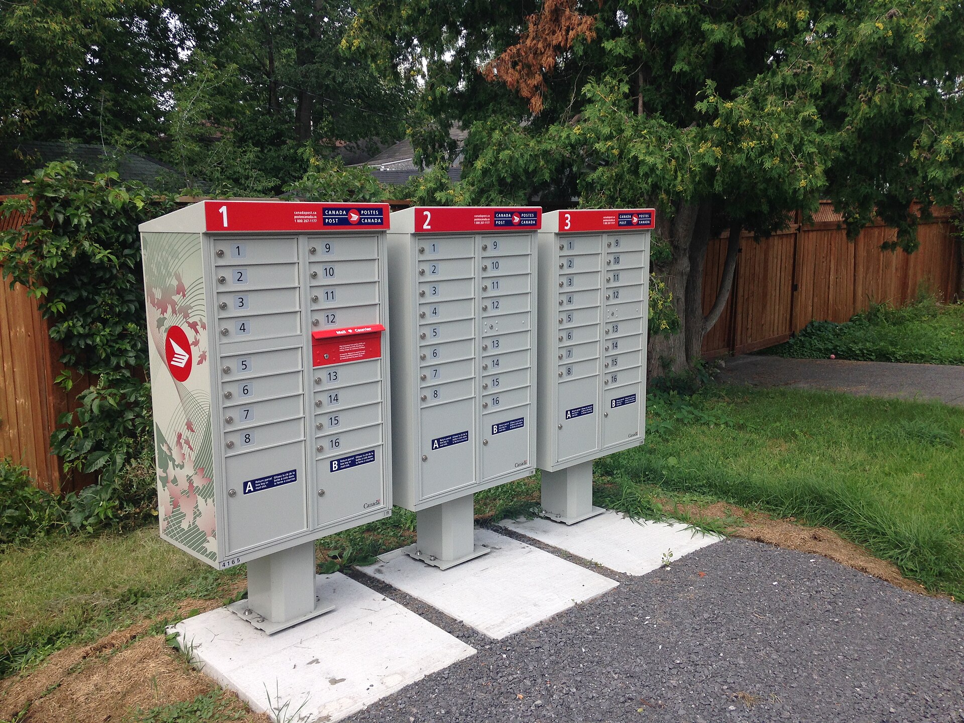 Grey community mailbox units on concrete pads beside a residential street in Ottawa
