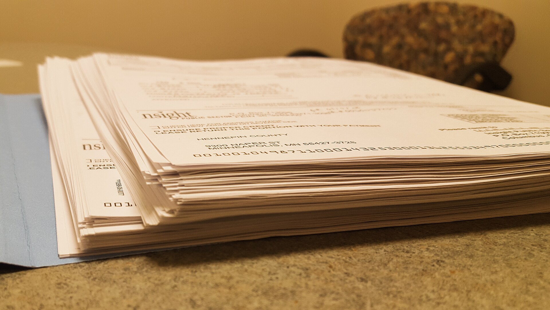 Thick stack of printed documents held in an open manila file folder on a table