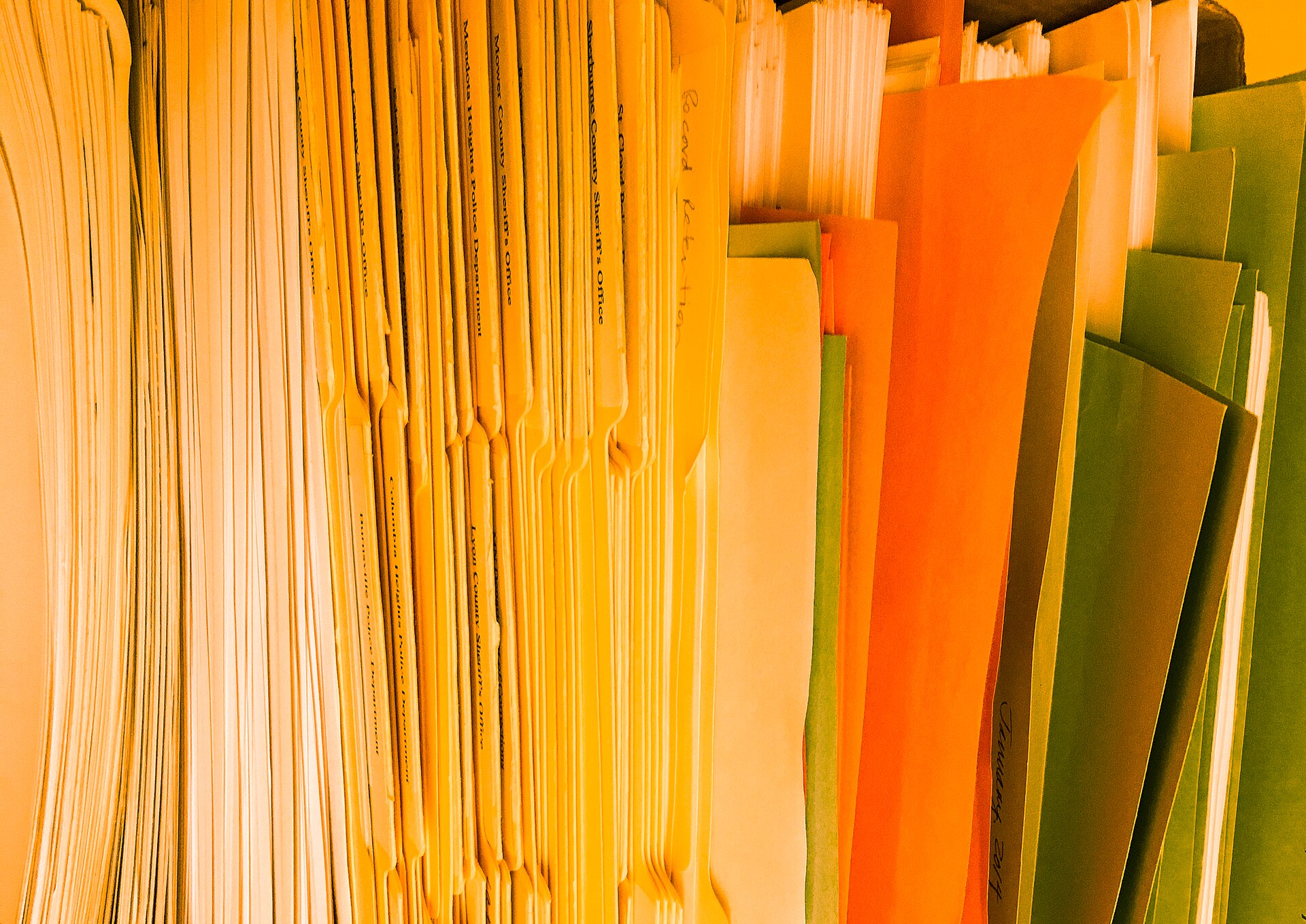 Rows of coloured hanging file folders packed into a filing drawer