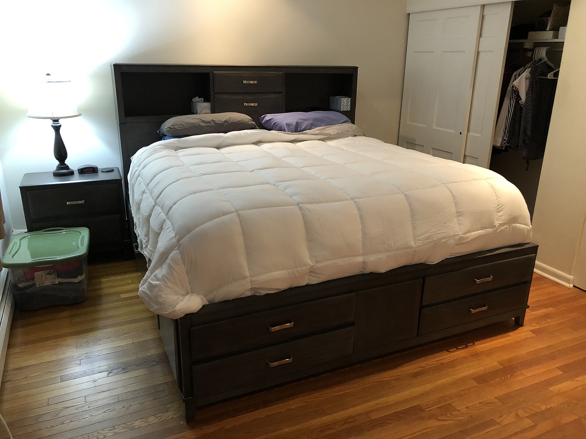 King-size storage bed with drawers filling much of a primary bedroom with hardwood floors