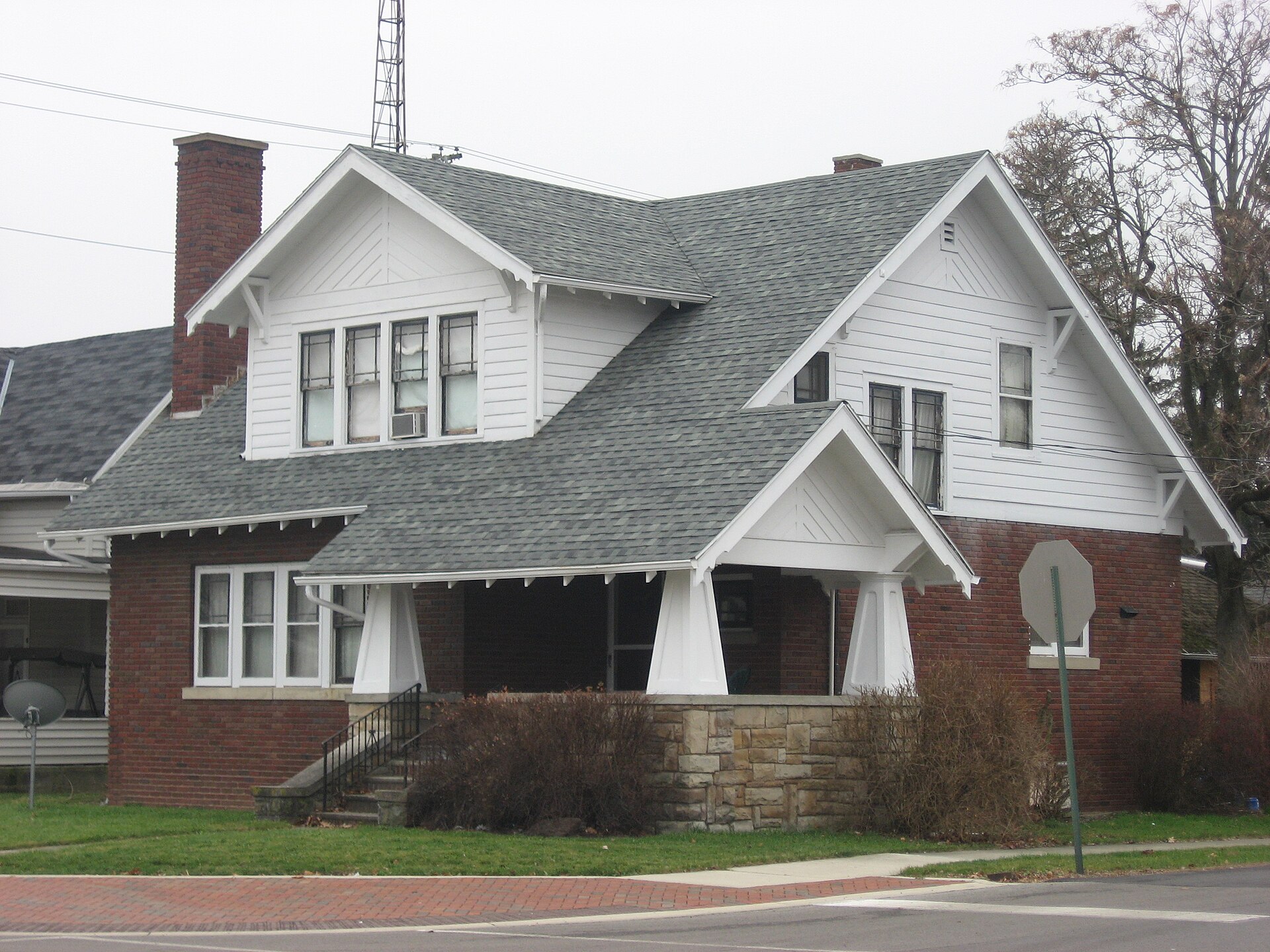 Older brick bungalow with a wide front porch and dormer on a corner lot