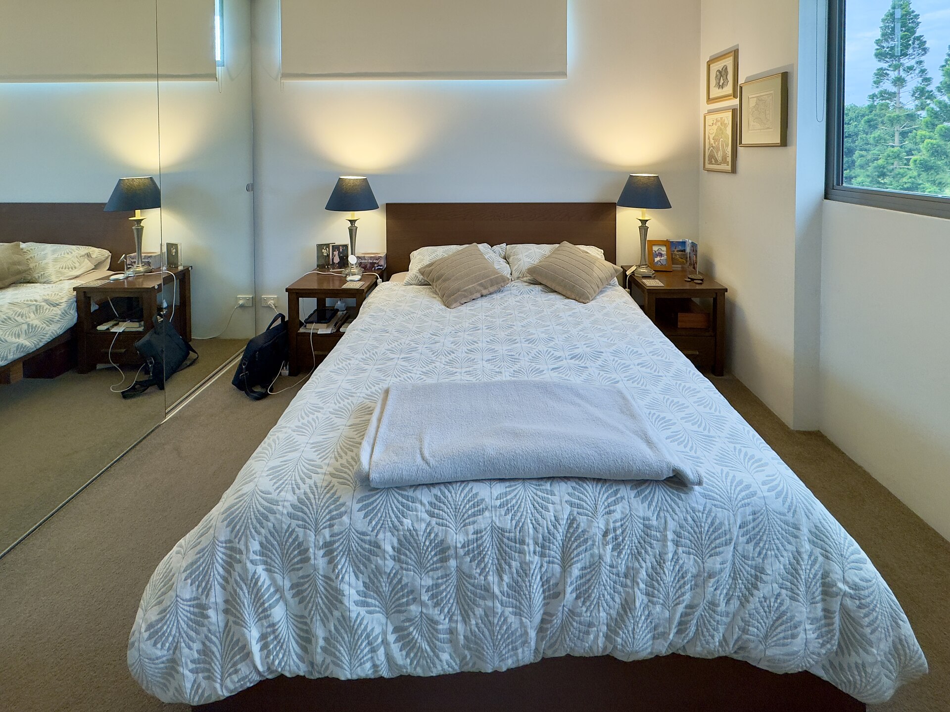 Bedroom with a queen bed centred between two nightstands and lamps, with a mirrored closet along one wall