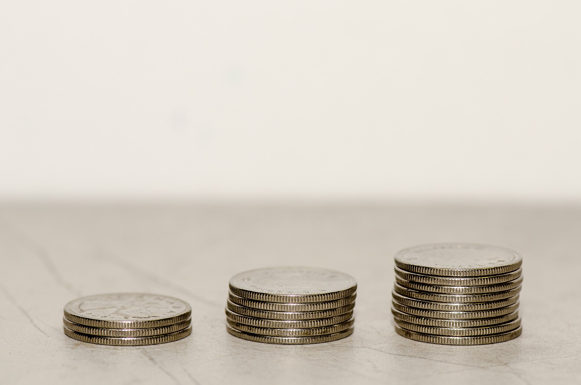 Three growing stacks of Canadian quarters on a white surface