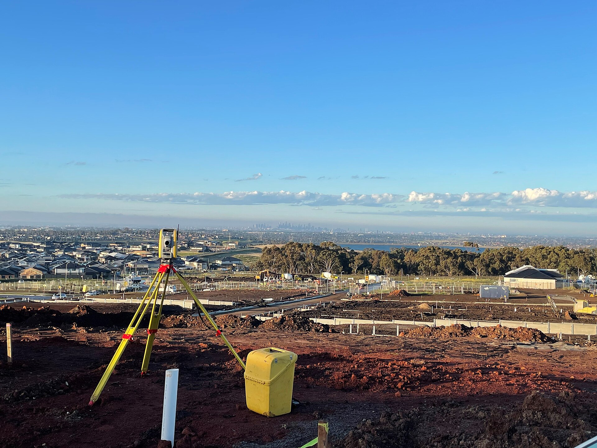 Surveying total station on a tripod overlooking earthworks and new homes at a residential development