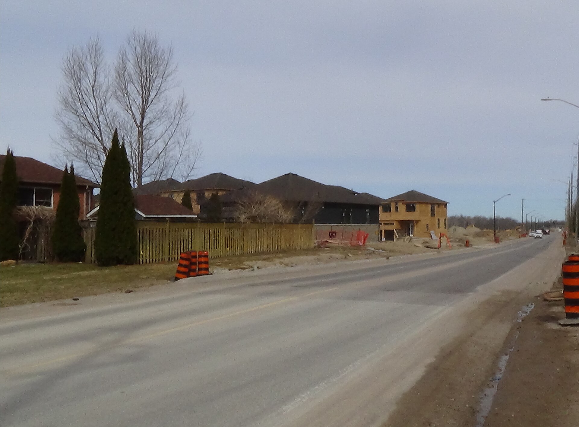 New homes, including one still in plywood sheathing, along a road in a Wasaga Beach subdivision under development
